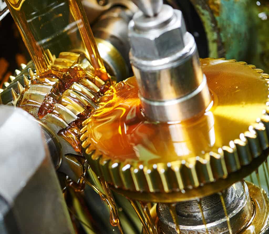 Close-up of industrial gears and machinery with oil lubrication.